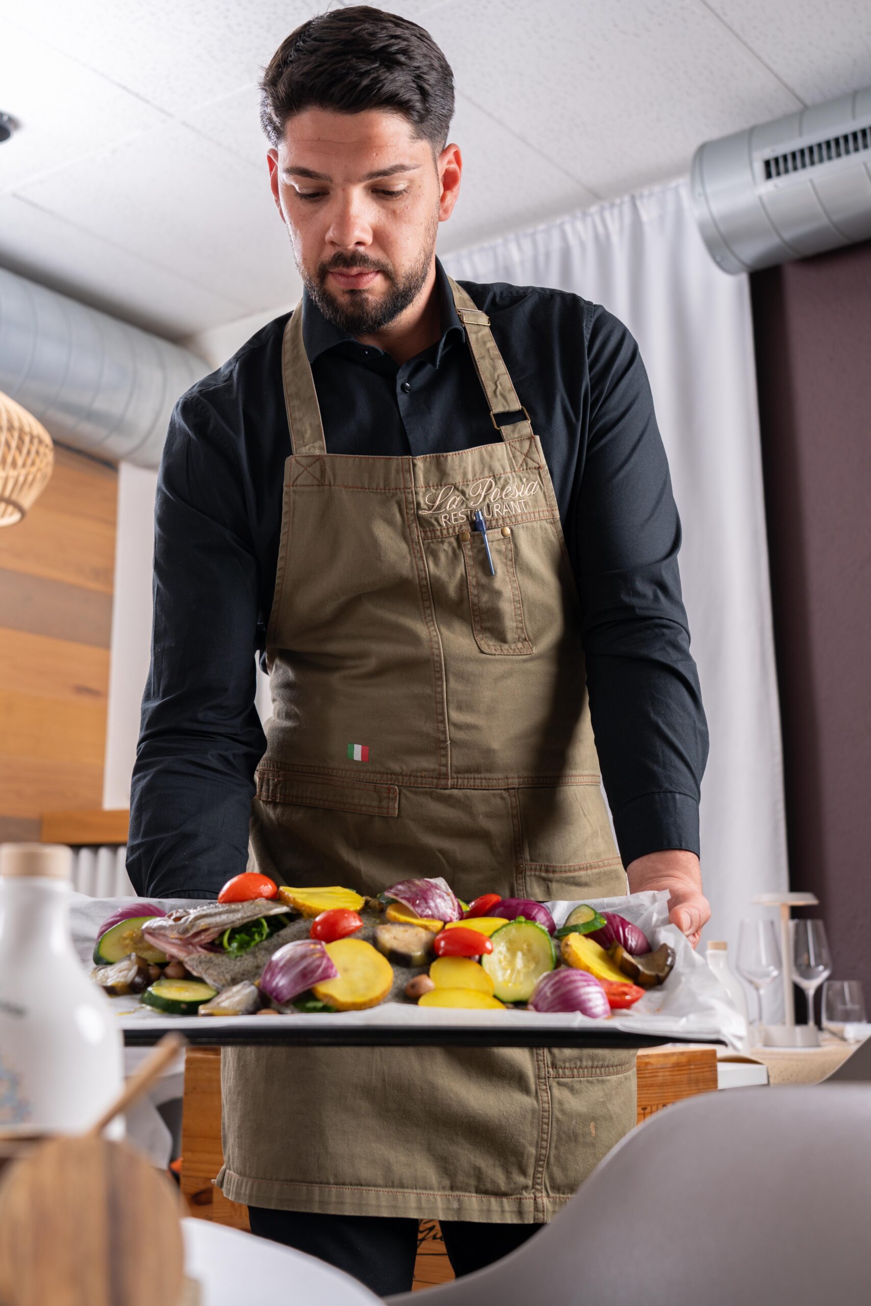 Angelo qui présente un poisson avant cuisson à table